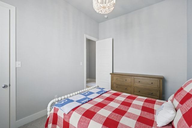 carpeted bedroom featuring baseboards and an inviting chandelier