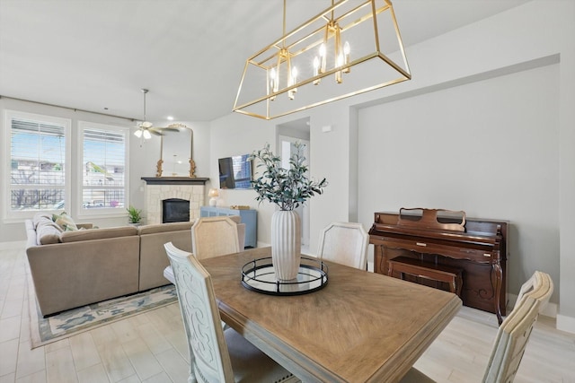 dining area featuring light wood-style floors, a ceiling fan, and a fireplace