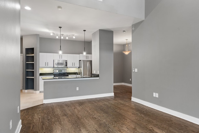 kitchen featuring dark wood-style floors, white cabinetry, stainless steel appliances, and dark countertops