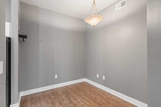 unfurnished room featuring visible vents, baseboards, and wood finished floors