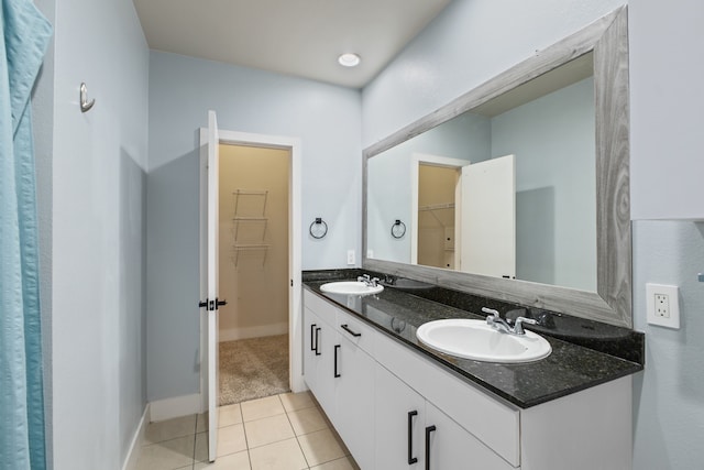 bathroom with tile patterned flooring, double vanity, a spacious closet, and a sink