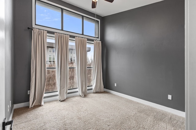 empty room featuring baseboards, carpet floors, and ceiling fan