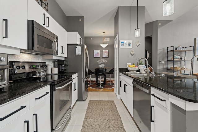 kitchen featuring light tile patterned floors, dark stone counters, a sink, stainless steel appliances, and tasteful backsplash