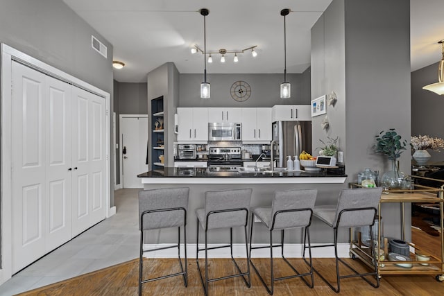 kitchen featuring visible vents, a breakfast bar, appliances with stainless steel finishes, dark countertops, and tasteful backsplash