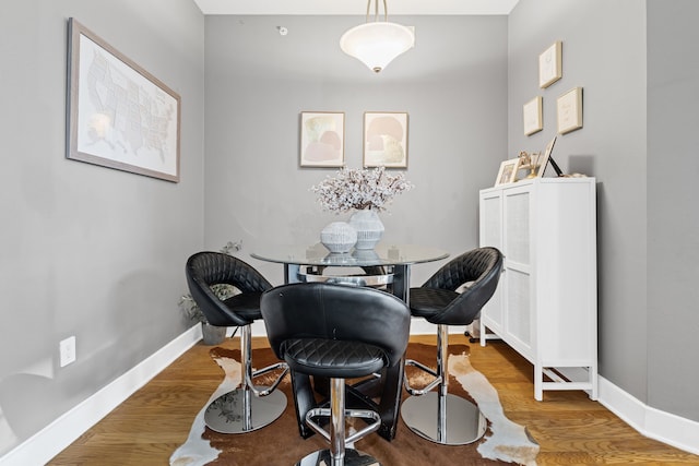 dining space with baseboards and wood finished floors