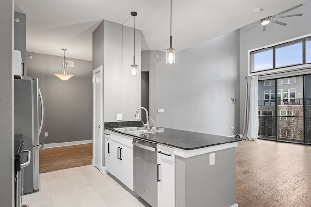 kitchen with a peninsula, a sink, hanging light fixtures, appliances with stainless steel finishes, and dark countertops