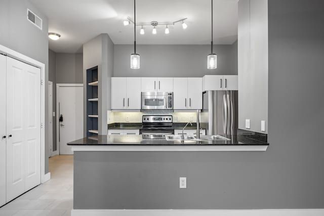 kitchen featuring a sink, dark countertops, backsplash, white cabinetry, and stainless steel appliances