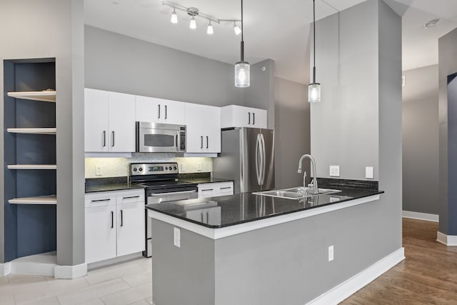 kitchen featuring a sink, decorative light fixtures, backsplash, stainless steel appliances, and a peninsula