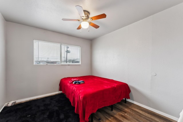 bedroom featuring baseboards, wood finished floors, and a ceiling fan