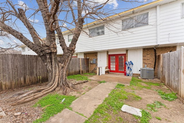 view of front of house featuring french doors, brick siding, central AC unit, and a fenced backyard