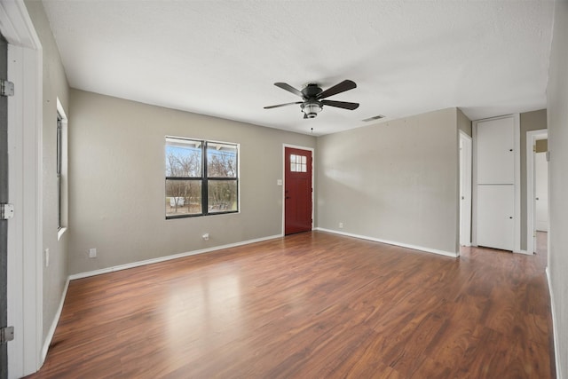 empty room featuring a ceiling fan, wood finished floors, baseboards, and a textured ceiling