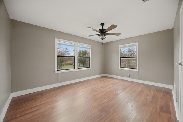 spare room with a ceiling fan, wood finished floors, and baseboards