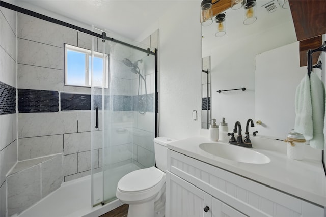 bathroom with visible vents, toilet, a stall shower, and vanity