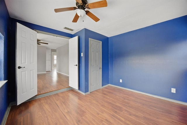 unfurnished bedroom with visible vents, wood finished floors, a closet, baseboards, and ceiling fan