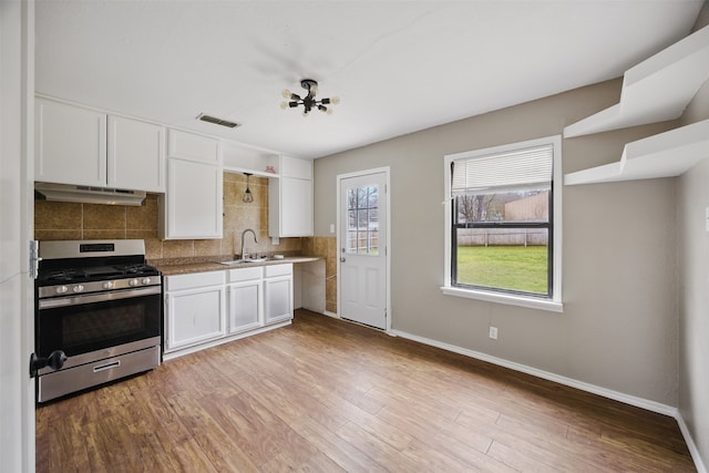 kitchen with visible vents, light wood finished floors, stainless steel range with gas cooktop, a sink, and under cabinet range hood