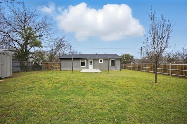 back of house featuring a yard, an outbuilding, and a fenced backyard