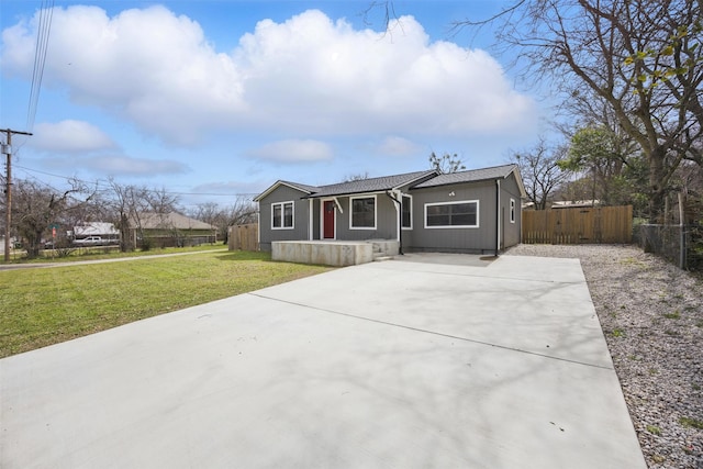 view of front facade featuring concrete driveway, a front yard, and fence