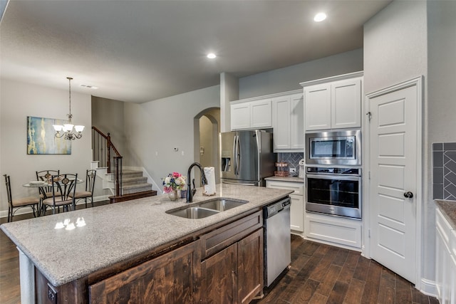 kitchen featuring backsplash, dark wood finished floors, appliances with stainless steel finishes, white cabinetry, and a sink