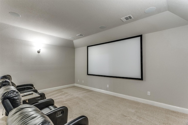 cinema with visible vents, light colored carpet, baseboards, and vaulted ceiling