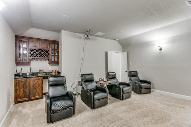 cinema room with visible vents, baseboards, wet bar, lofted ceiling, and light carpet