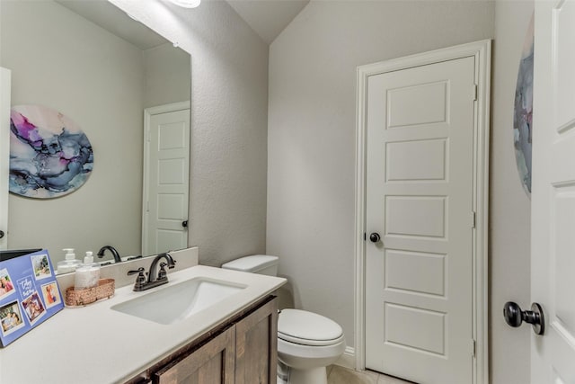 half bathroom featuring tile patterned flooring, toilet, and vanity