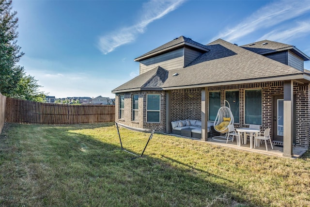 back of property with a yard, brick siding, a fenced backyard, and a patio area