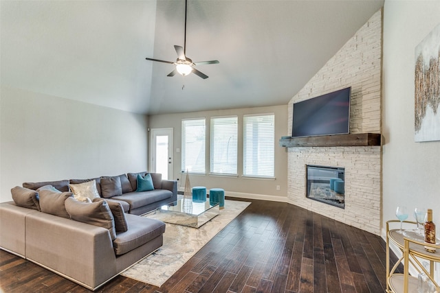 living area with dark wood finished floors, a stone fireplace, high vaulted ceiling, and a ceiling fan