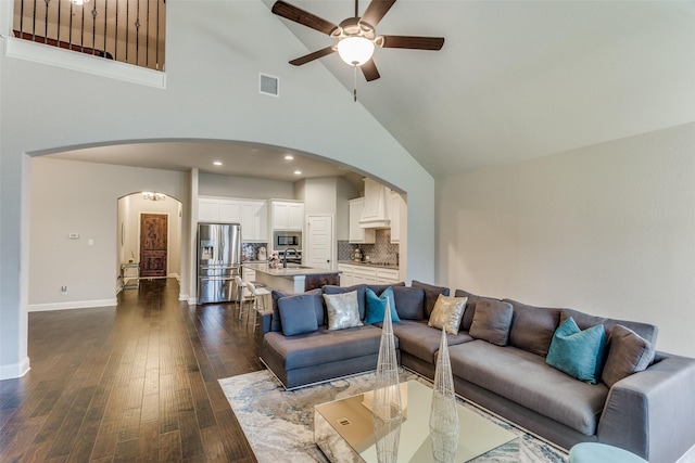 living room with dark wood finished floors, visible vents, arched walkways, and a ceiling fan