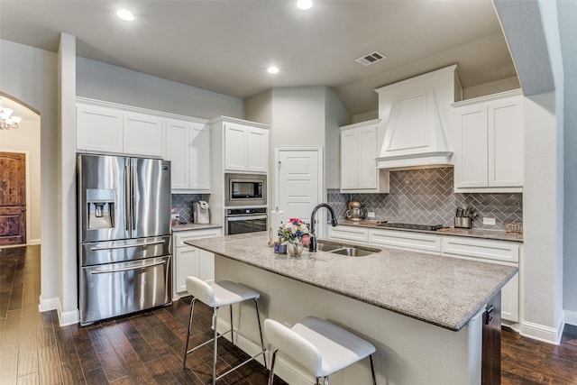 kitchen featuring dark wood-style floors, visible vents, a sink, custom range hood, and appliances with stainless steel finishes