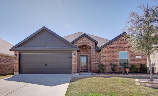 view of front of house featuring a front yard, a shingled roof, concrete driveway, a garage, and brick siding