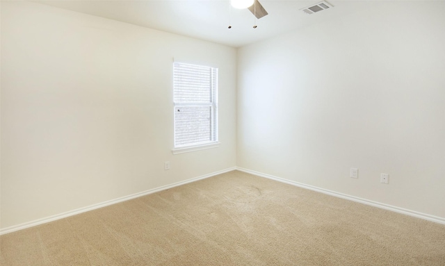 empty room featuring visible vents, light colored carpet, baseboards, and ceiling fan