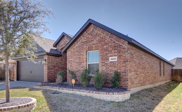 view of side of home featuring brick siding, a shingled roof, concrete driveway, a yard, and an attached garage