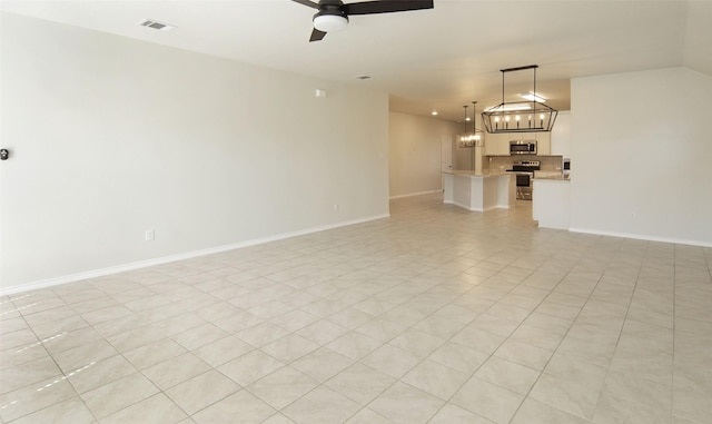 unfurnished living room featuring visible vents, ceiling fan with notable chandelier, and baseboards