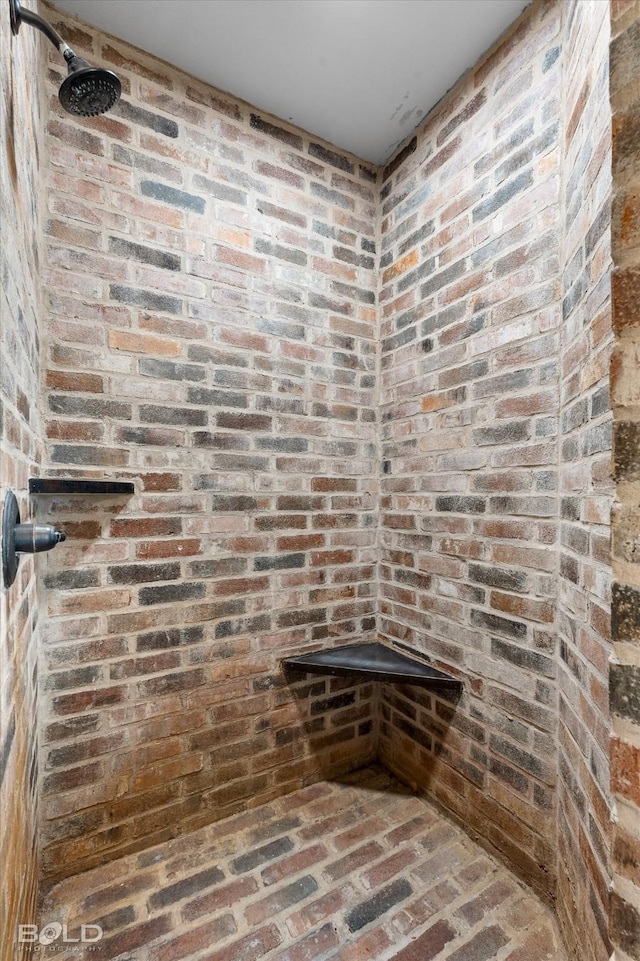 full bath featuring brick floor and a tile shower