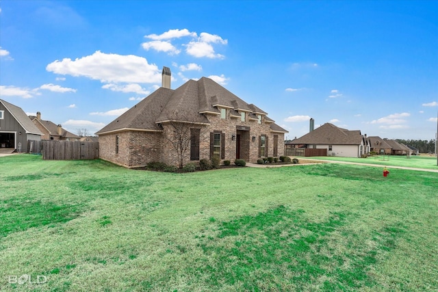 view of front of home with brick siding, a chimney, a front lawn, and fence