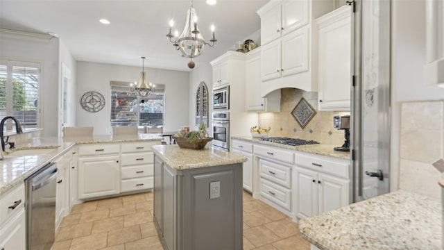 kitchen featuring a sink, white cabinetry, stainless steel appliances, an inviting chandelier, and decorative backsplash