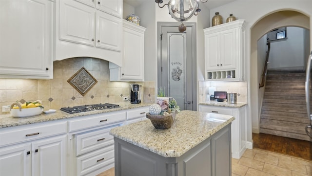 kitchen with white cabinetry, light stone countertops, arched walkways, and stainless steel gas cooktop