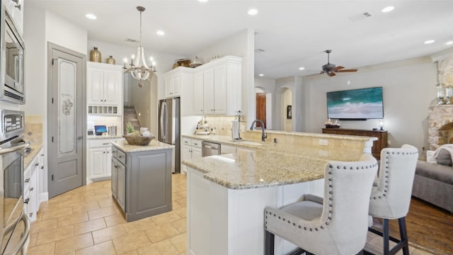 kitchen with visible vents, decorative backsplash, appliances with stainless steel finishes, a peninsula, and a sink