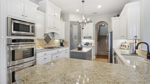 kitchen with white cabinets, stainless steel appliances, backsplash, and a sink