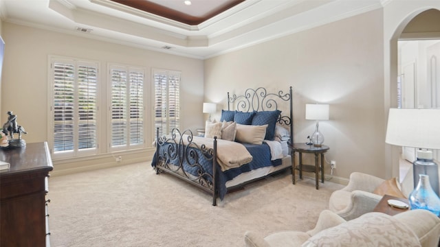 bedroom with a tray ceiling, visible vents, carpet, and crown molding