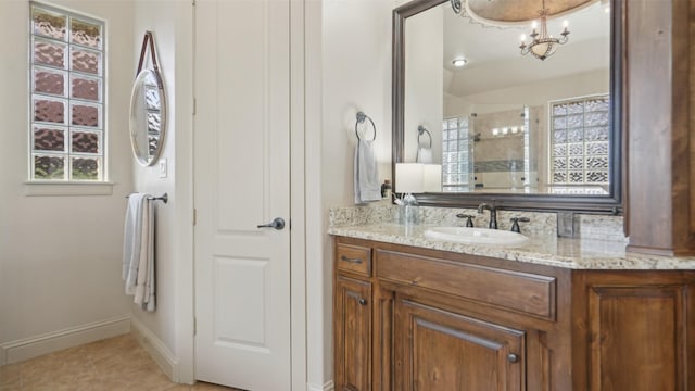 bathroom featuring vanity, baseboards, tiled shower, tile patterned floors, and a notable chandelier