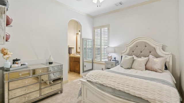 bedroom featuring visible vents, ornamental molding, ensuite bath, arched walkways, and light colored carpet