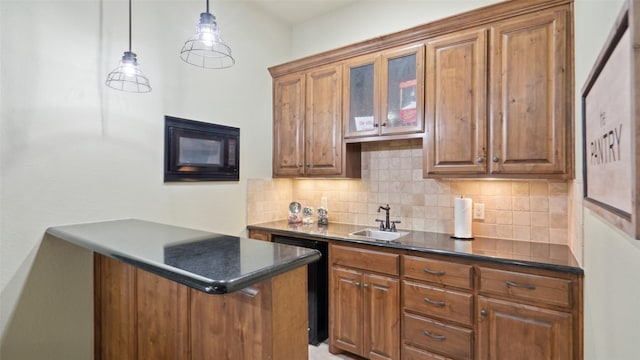 kitchen featuring dark countertops, brown cabinets, tasteful backsplash, and a sink