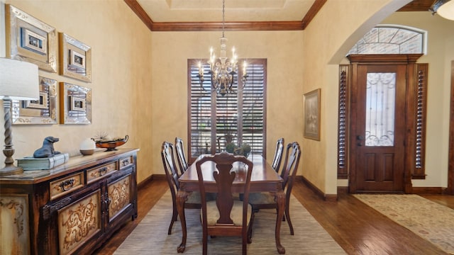 dining area featuring dark wood-style floors, arched walkways, crown molding, baseboards, and a chandelier