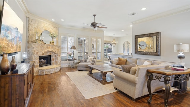 living area with visible vents, dark wood-type flooring, ornamental molding, ceiling fan with notable chandelier, and a fireplace