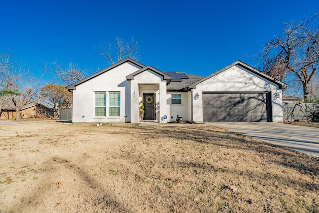 view of front of home with a garage, roof mounted solar panels, brick siding, and concrete driveway