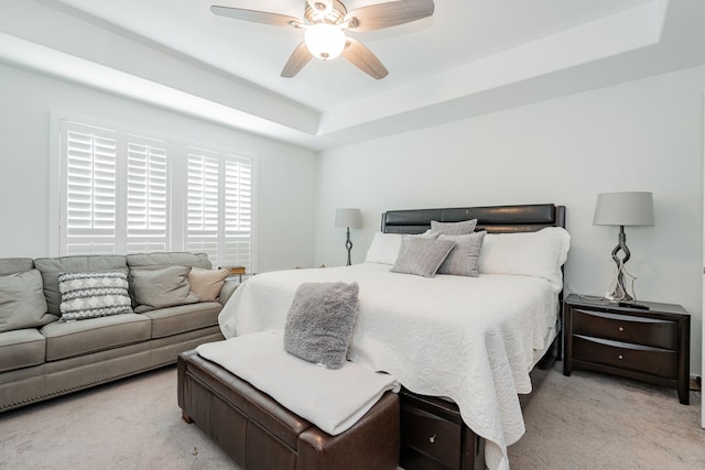 bedroom featuring a tray ceiling, light colored carpet, and ceiling fan