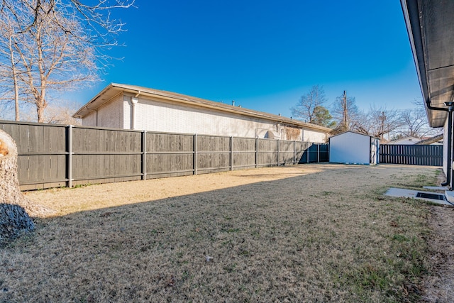 view of yard featuring a storage unit, an outbuilding, and a fenced backyard