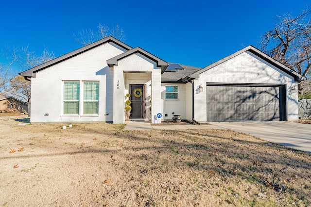 single story home with brick siding, solar panels, driveway, and a garage