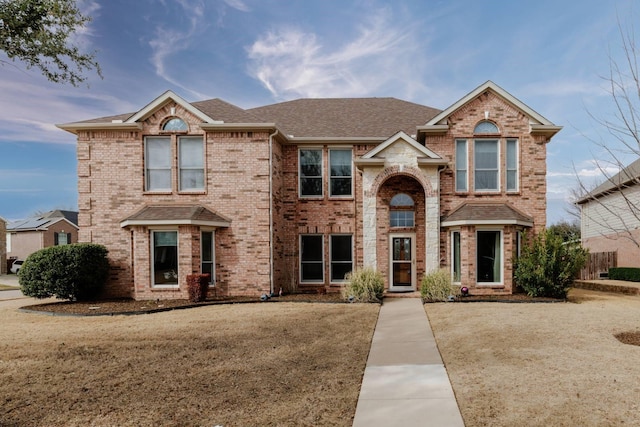 traditional home featuring brick siding and a shingled roof